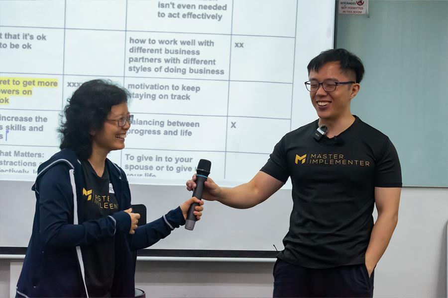 Marc holding the mic out to a laughing attendee.